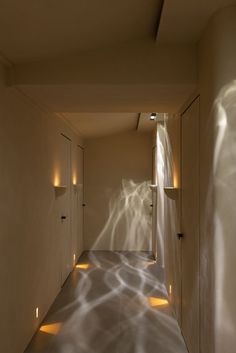 an empty hallway with light coming through the walls and shadows on the wall behind it