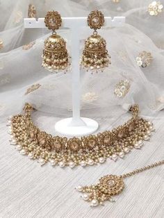 a necklace and earring set with pearls on display in front of a white background