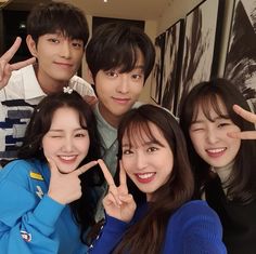 four young people posing for the camera with their fingers in the shape of two peace signs