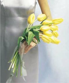 a woman in a silver dress holding yellow tulips