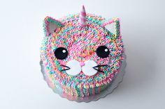 a cupcake decorated with sprinkles and a cat's face