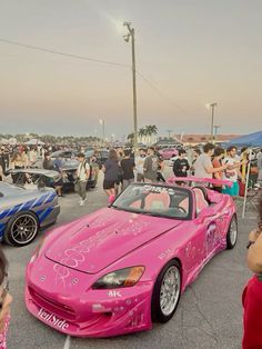 pink sports cars parked in a parking lot with people standing around and looking at them