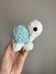 a hand holding a small crocheted turtle