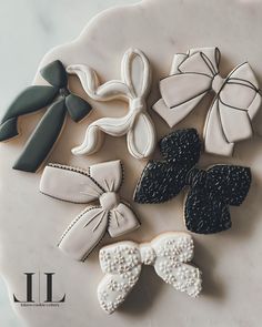 decorated cookies are arranged on a plate with black and white bows, bow ties, and ribbons