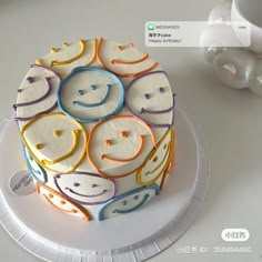 a cake decorated with smiley faces on top of a white plate next to a cup