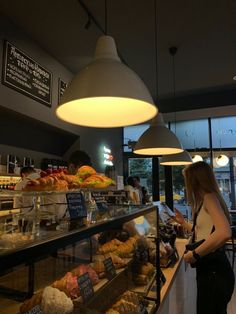 a woman standing in front of a display case filled with donuts and pastries