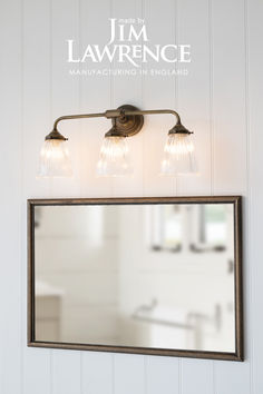 a bathroom vanity with three lights and a mirror above it that says i'm lawrencece manufacturing in england