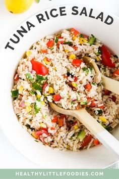 a white bowl filled with rice and vegetables next to a lemon wedge on top of a table