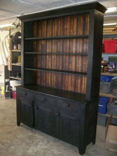 an old black bookcase with wooden doors and drawers in a room filled with other items