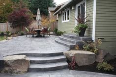 an outdoor patio with steps leading up to the back door and dining table in the background