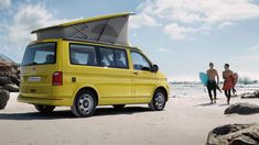 two surfers walking towards a yellow van on the beach