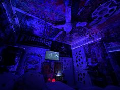 a room with purple lights and graffiti on the walls, ceiling and bedding in it