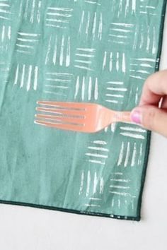 a person holding a fork on top of a piece of green paper with white lines