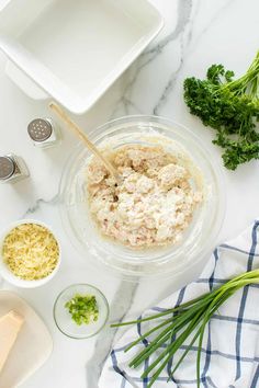 ingredients to make tuna salad laid out on a marble counter top, including parmesan cheese and broccoli