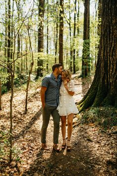 a man and woman are standing in the woods