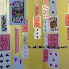 several cards are hanging from the ceiling in front of a yellow wall that is decorated with red and white playing cards