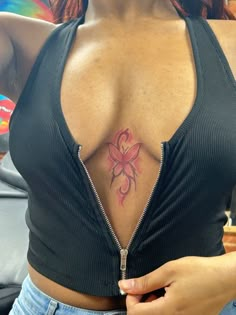 a woman with a pink tattoo on her chest holding a cell phone in her hand