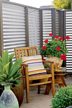 a wooden chair sitting on top of a patio next to a potted plant with red flowers