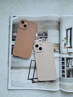 an open magazine with two iphone cases on top of it and a coffee table in the background