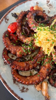 an octopus dish on a white plate with garnishes and seasoning sprinkles