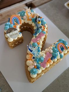 a cake shaped to look like the letter e is decorated with rainbows and clouds