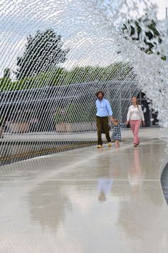 two people are walking through a water fountain