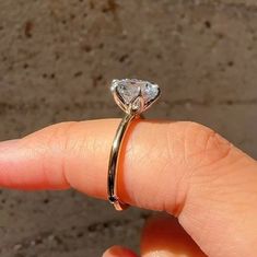 a woman's hand holding a ring with a diamond on it