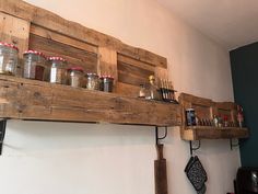 wooden shelves holding jars and spices on top of a kitchen counter with utensils hanging from them