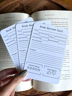 three book review cards held in front of an open book