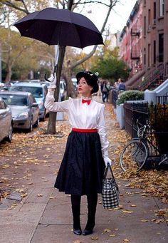 a woman holding an umbrella while standing on a sidewalk