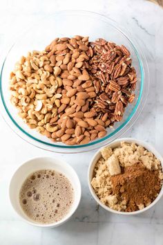 nuts, cocoa and other ingredients in bowls on a marble counter top with a glass bowl