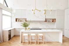 a white kitchen with marble counter tops and stools