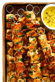 chicken skewers with mustard sauce and parsley garnish on a tray