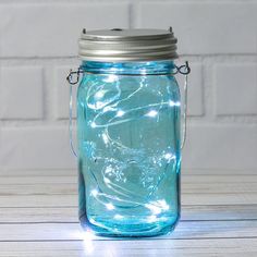 a blue mason jar with fairy lights in it