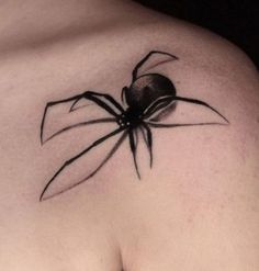 a black spider tattoo on the back of a woman's left shoulder and chest