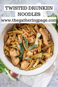 a white bowl filled with noodles and chicken on top of a marble table next to greens