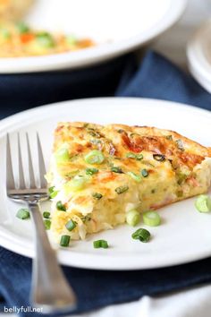 a slice of quiche on a white plate with a fork next to it and another dish in the background