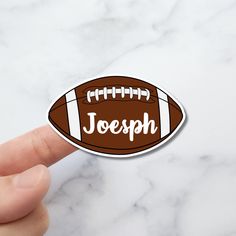 a hand holding a football shaped sticker that says, joseph on the inside of it