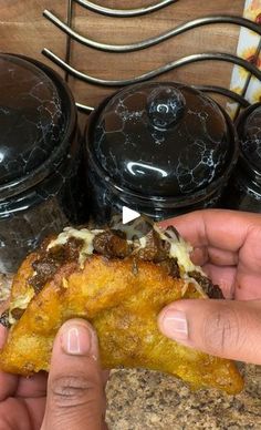 a person holding up a piece of food in their hand next to some black containers