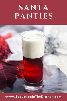 a glass filled with liquid sitting on top of a table next to poinsettis