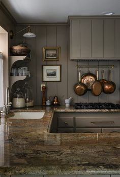 a kitchen counter with pots and pans hanging on the wall next to an oven