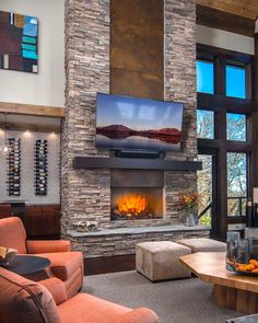 a living room with a large stone fireplace and television mounted on the wall above it