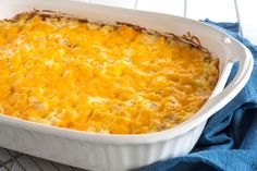 a casserole dish on a cooling rack with a blue towel next to it