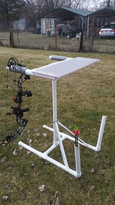 a white table sitting on top of a grass covered field next to a bow and arrow