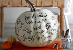 a white pumpkin with writing on it sitting on a table next to markers and pens