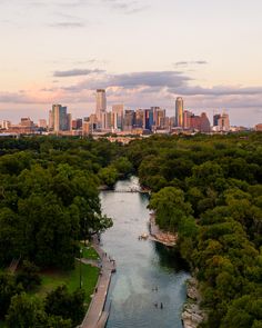 an aerial view of a city and river in the foreground with trees on both sides