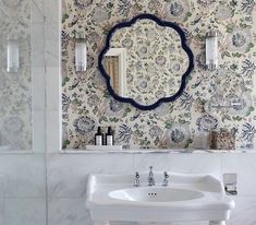 a white sink sitting under a bathroom mirror next to a wall mounted faucet