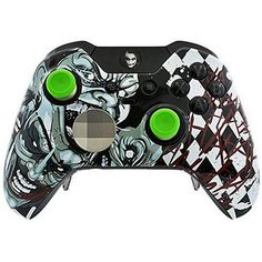 a black and white video game controller with green buttons on the front, and an evil face painted on the side