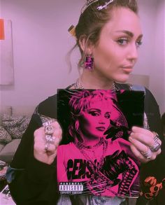 a woman holding up a pink poster in front of her face and wearing some jewelry