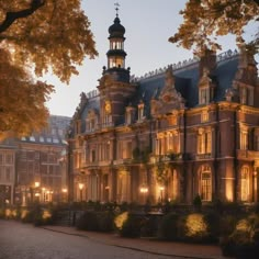 an old building lit up at night with lights on the windows and trees in front